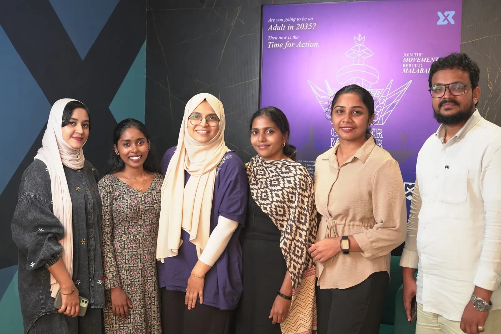 The PerpeX team in front of the Rebuild Malabar campaign poster